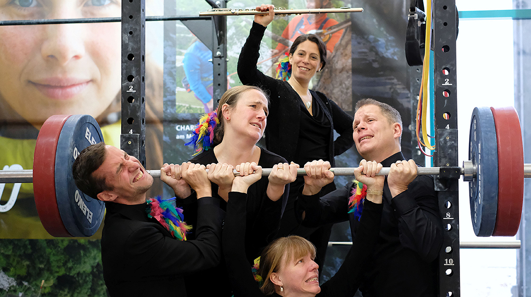 Fünf Musiker stemmen eine Gewichtstange