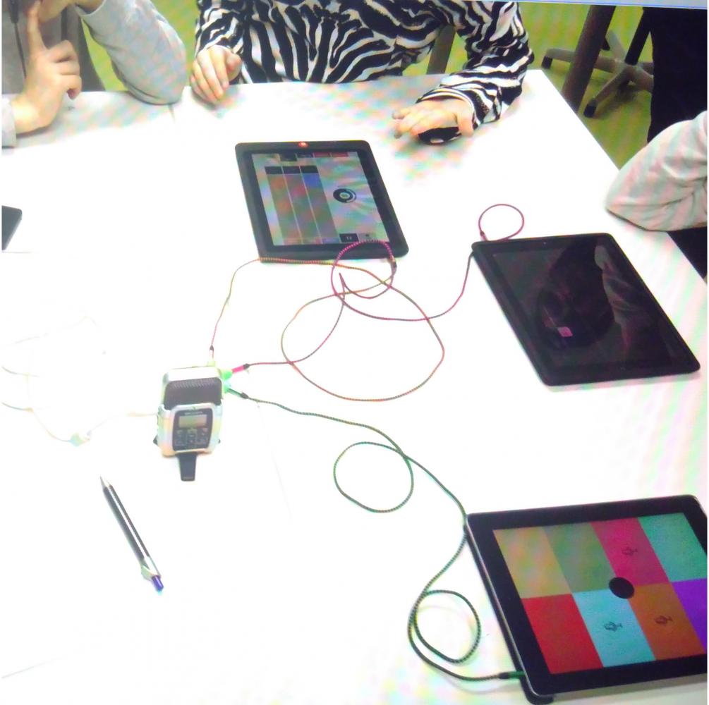 Tisch auf dem verschieden Tabletts liegen und mit Kabel verbunden sind. Die Menschen machen Musik 